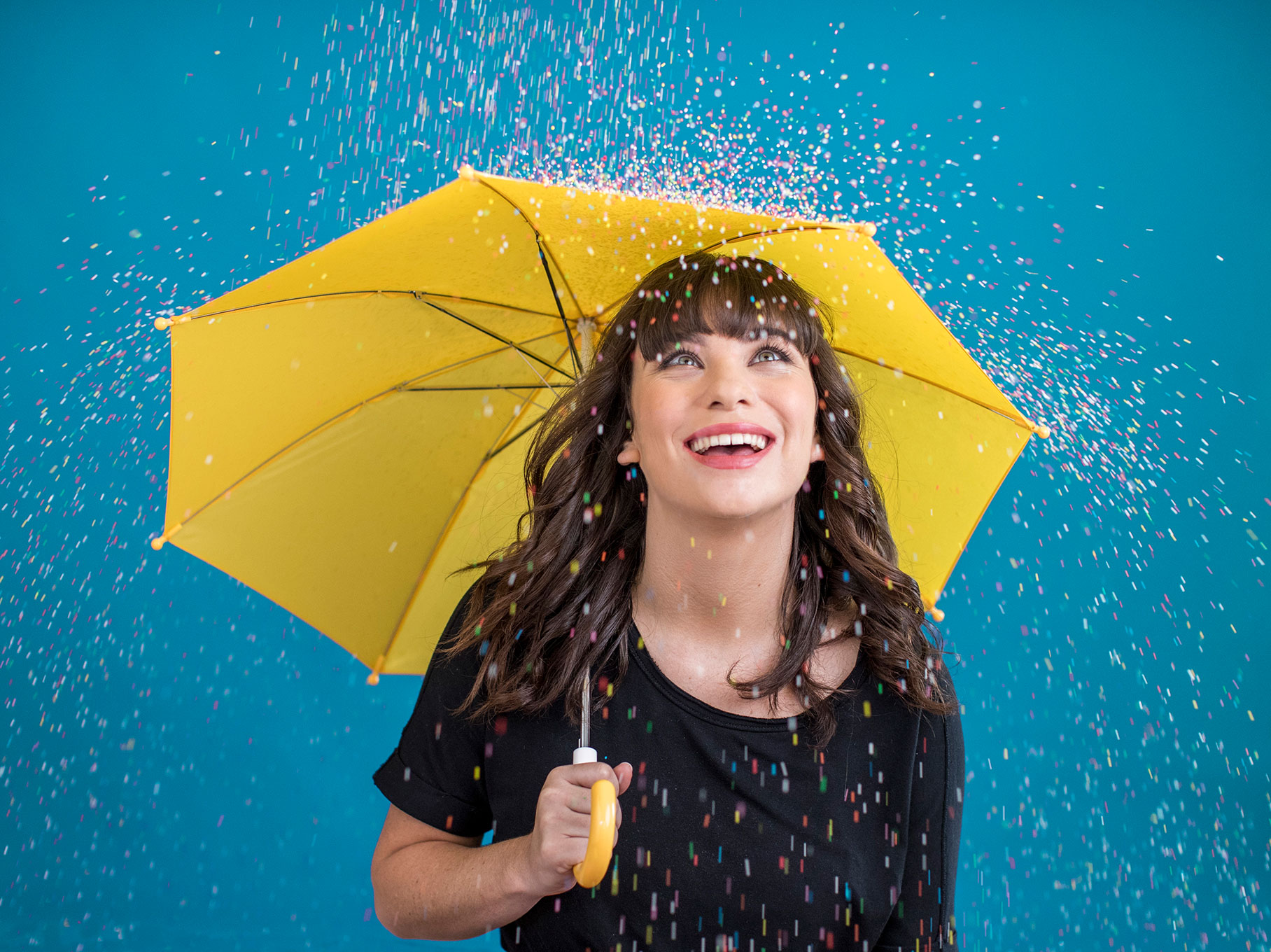 Girl holding umbrella with hundreds and thousands falling from the sky